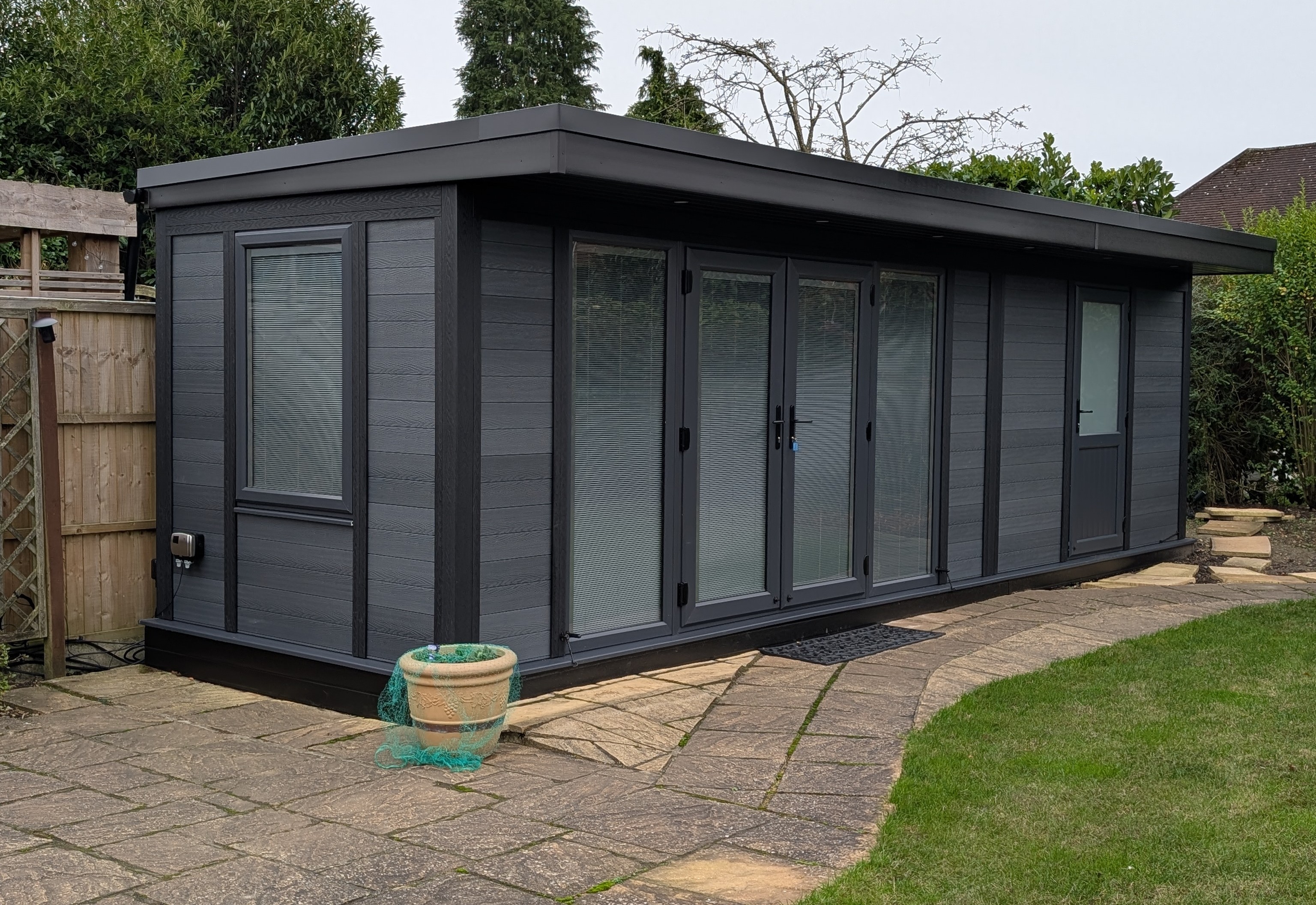 Long charcoal-grey garden room with integrated blinds and storage