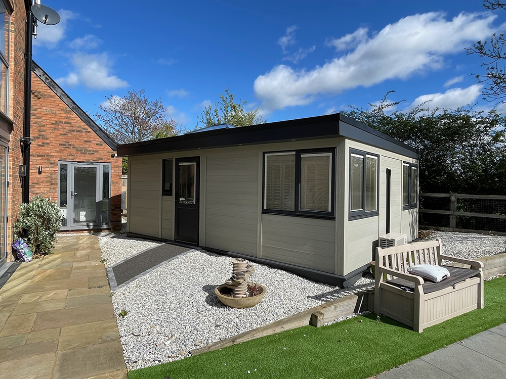 Garden annexe exterior with light cladding, dark frames and gravel surround
