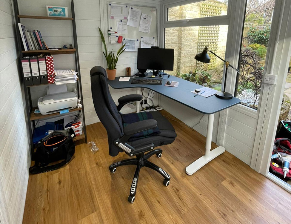 Garden office interior with standing desk, shelving, and natural light