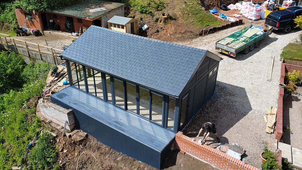 Custom large composite garden room with pitched slate roof and full-height glazing under construction