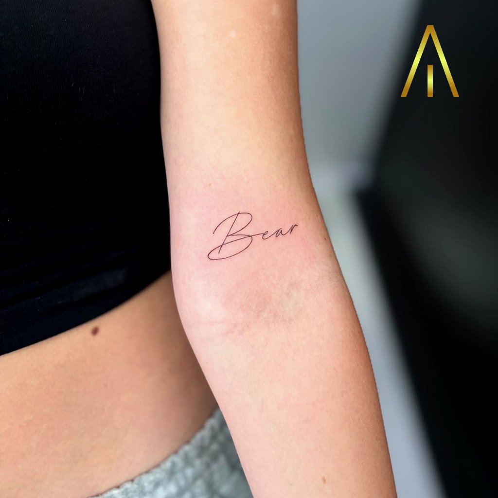 Fine line Bear script tattoo on upper arm Chiang Mai