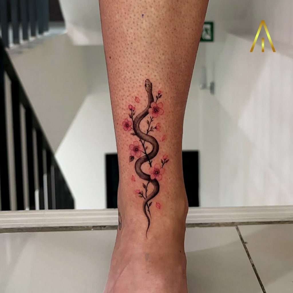 Minimal snake and cherry blossom tattoo on the lower leg by Katie, Artisan Ink Chiang Mai