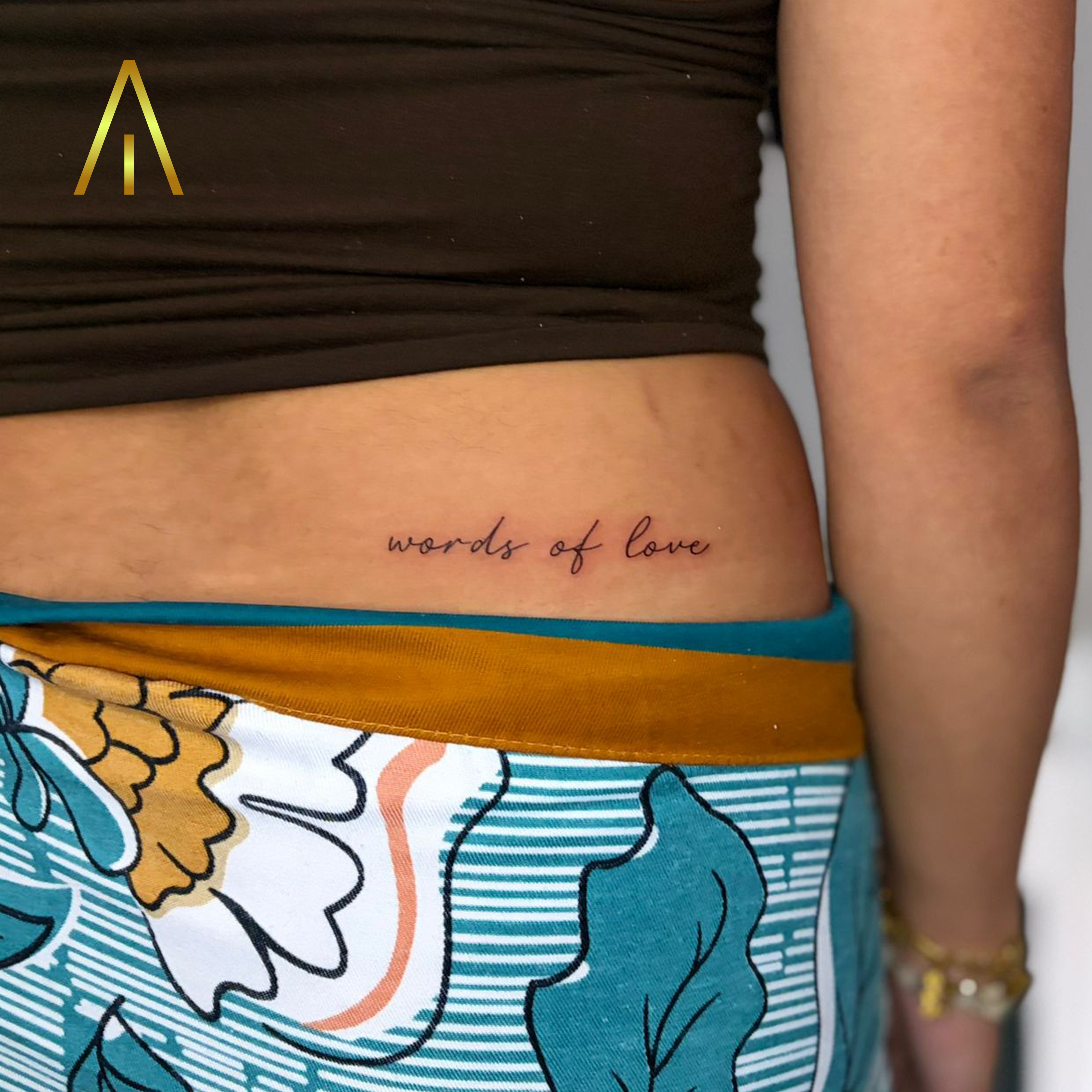 Fine line words of love script lower back tattoo Chiang Mai