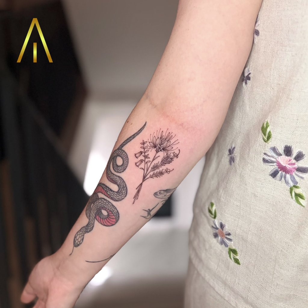 Fine line serpent and wildflowers tattoo on forearm Chiang Mai