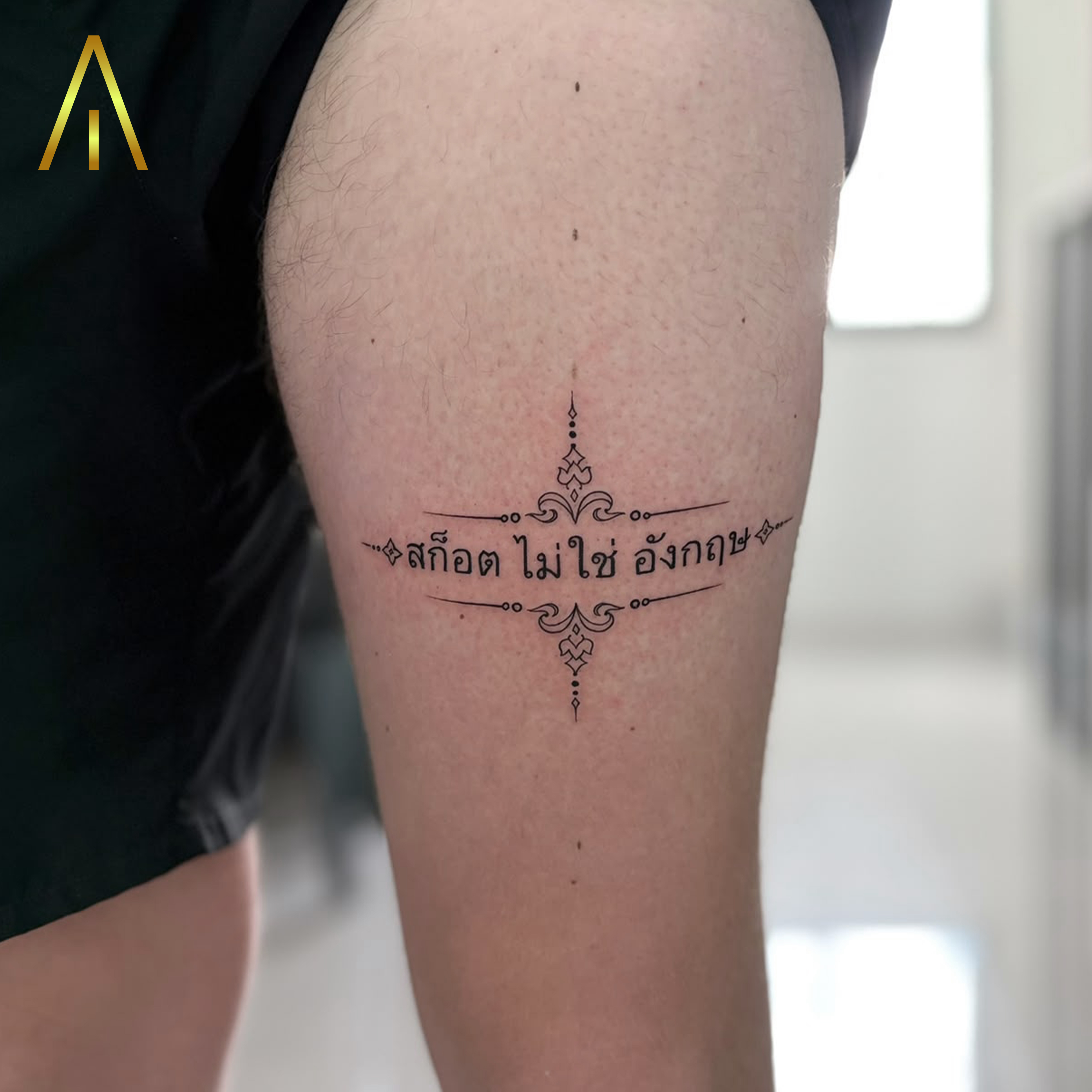 Katie Thai script with ornamental filigree minimal thigh tattoo Chiang Mai
