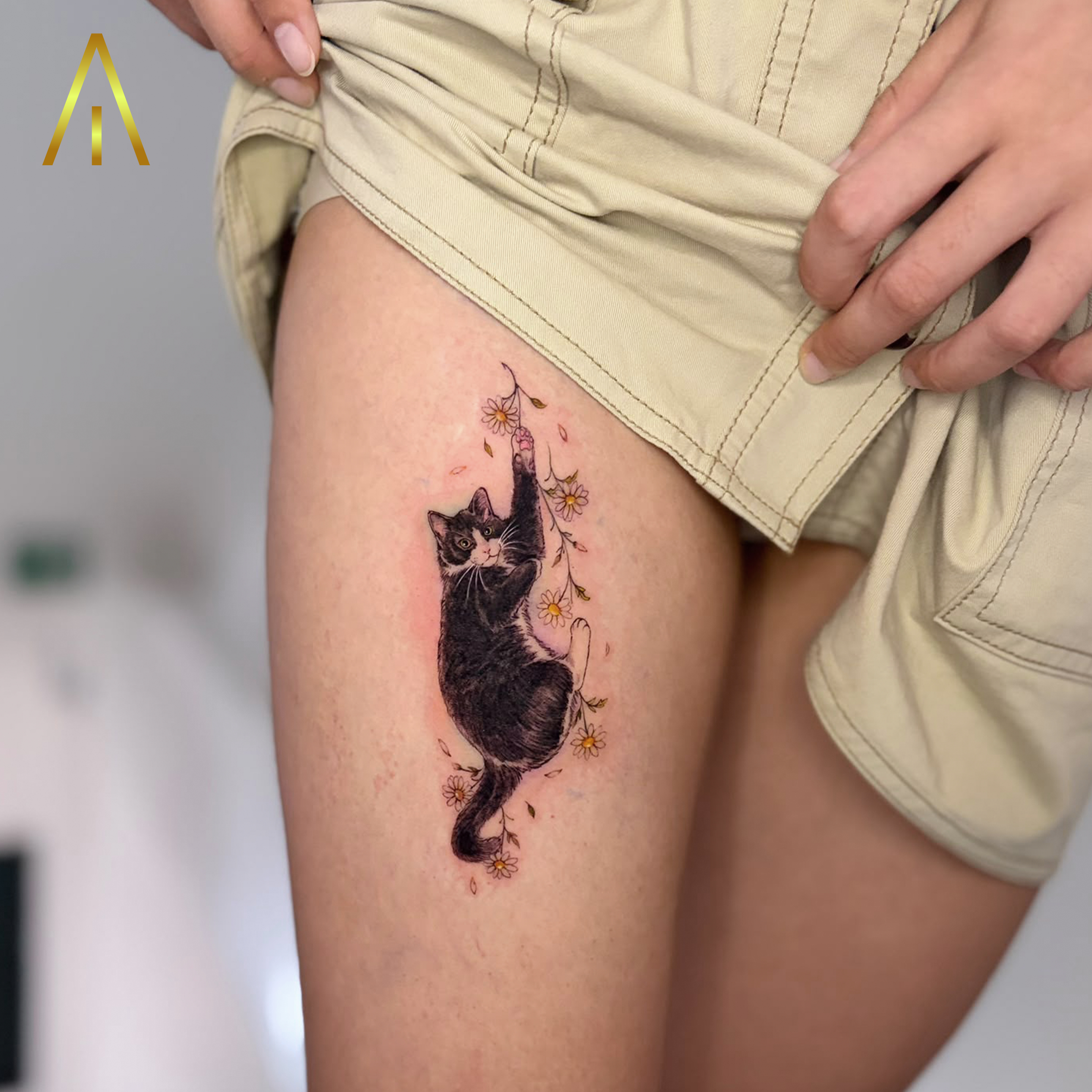 Minimal black and white cat with daisies thigh tattoo Chiang Mai