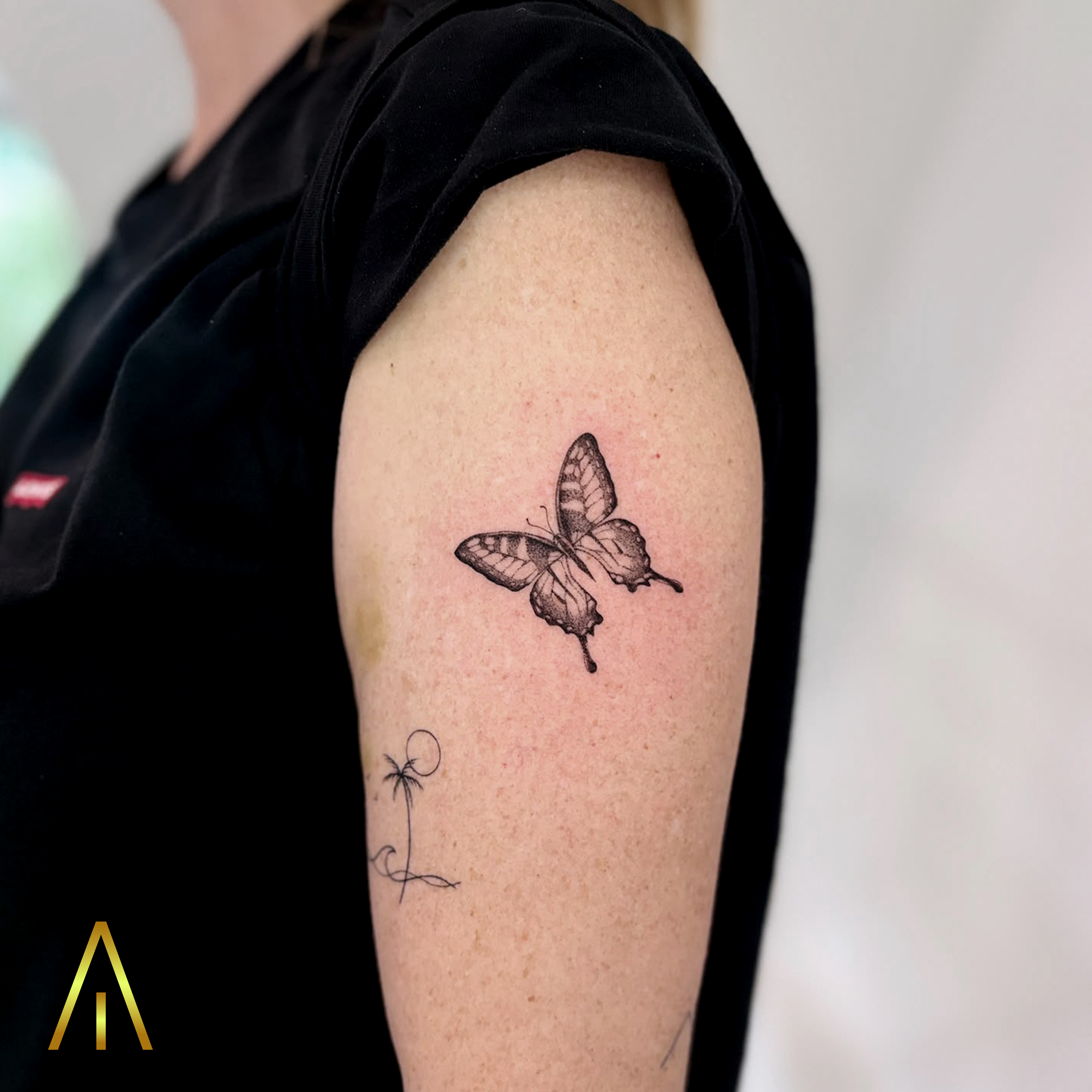 Minimal butterfly and palm tree upper arm tattoo Chiang Mai
