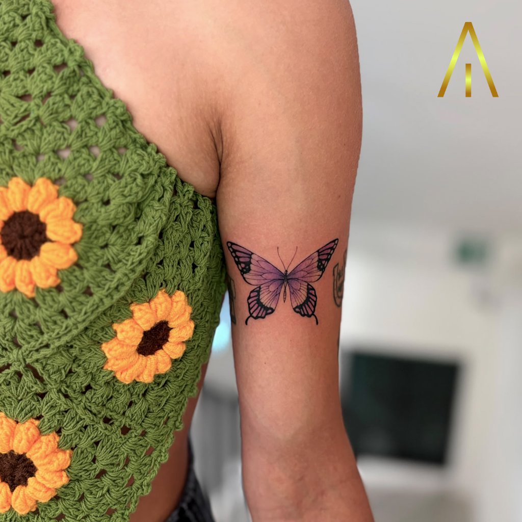 Minimal purple butterfly tattoo on upper arm Chiang Mai