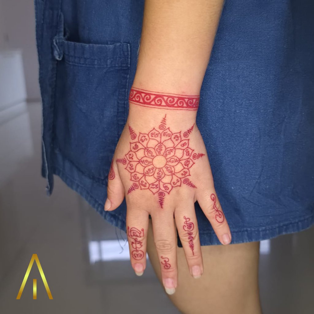 Sak Yant red ink mandala tattoo on hand and wrist Chiang Mai