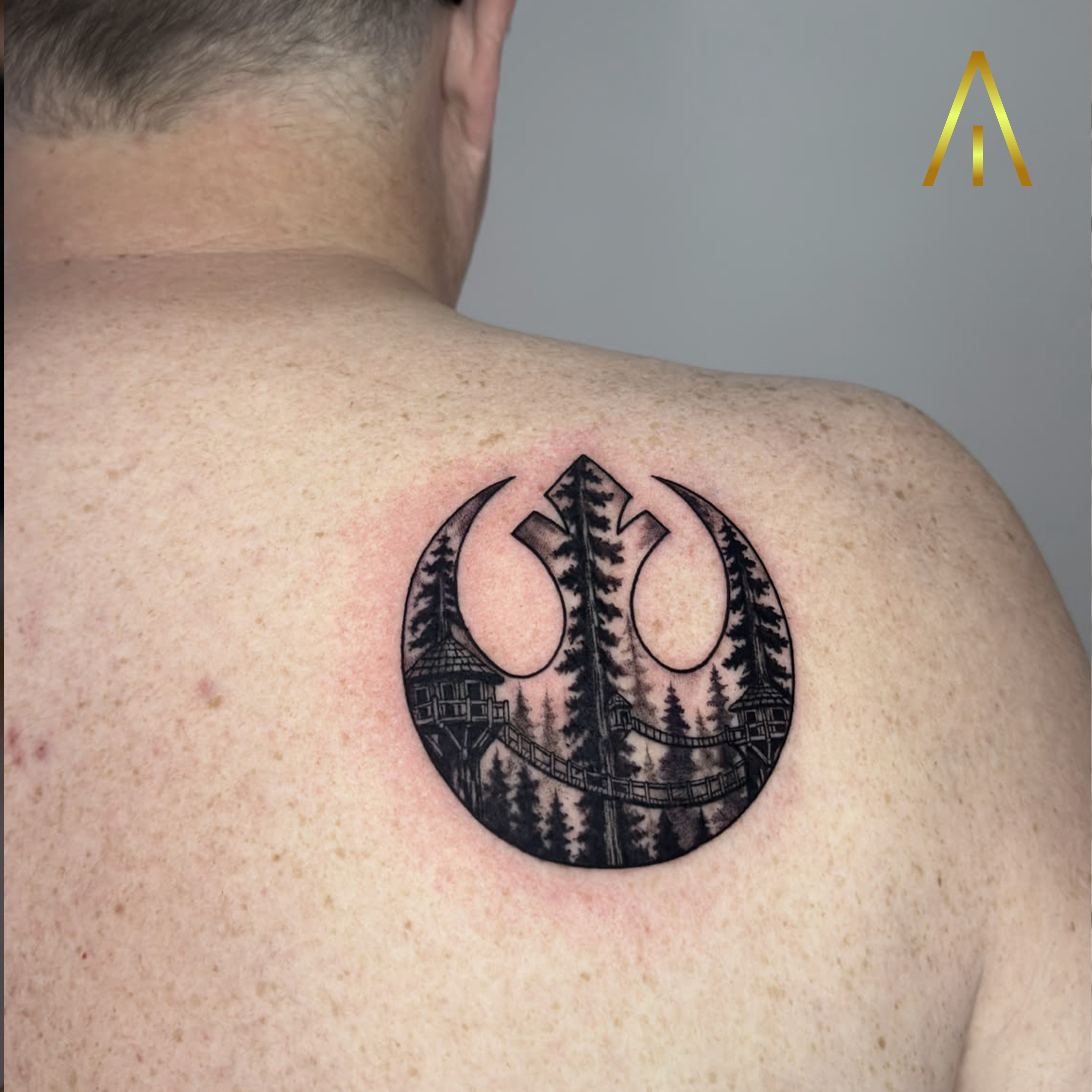 Katie Rebel Alliance symbol forest scene blackwork upper back tattoo Chiang Mai