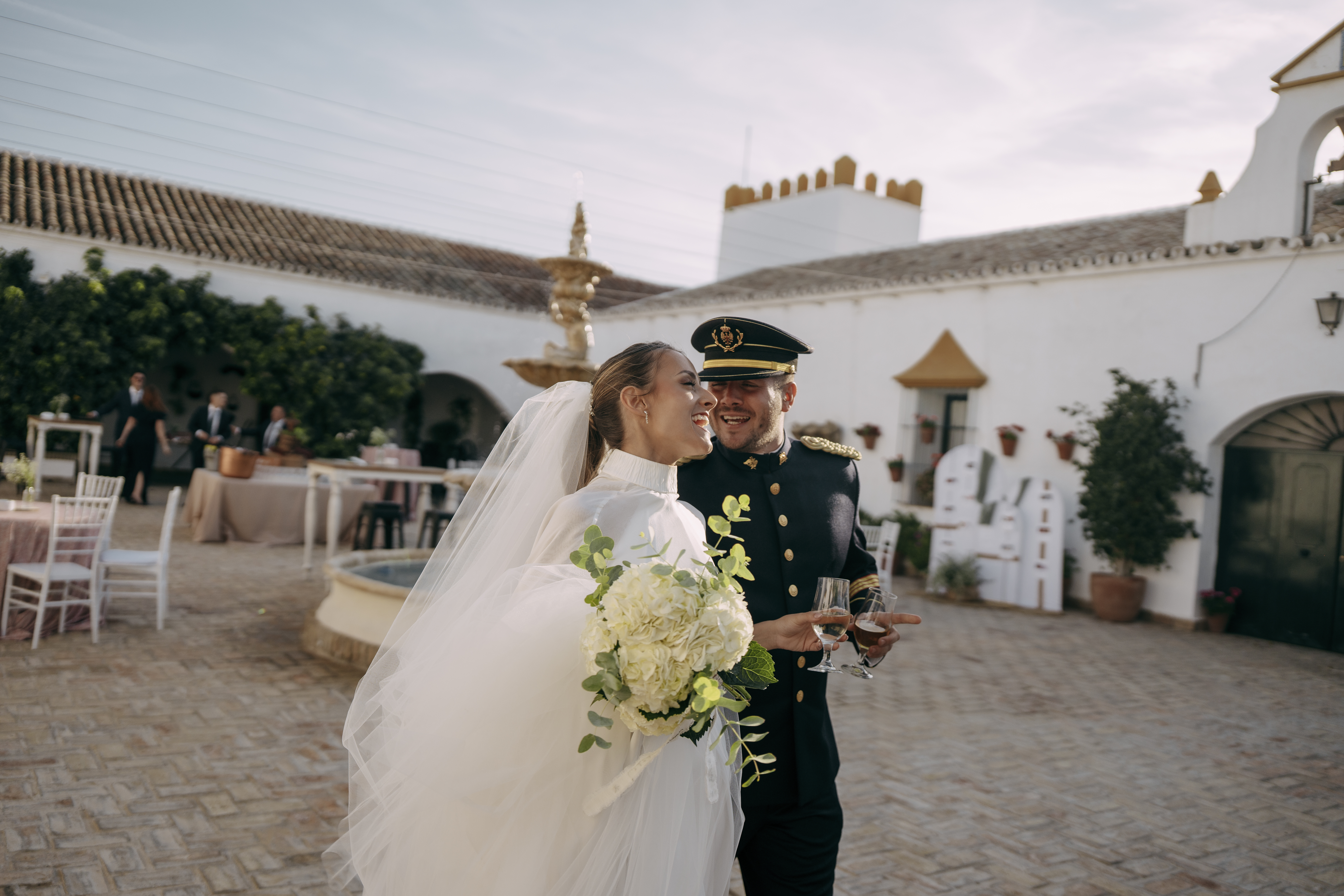 Novios riendo durante la celebración en un patio con fuente