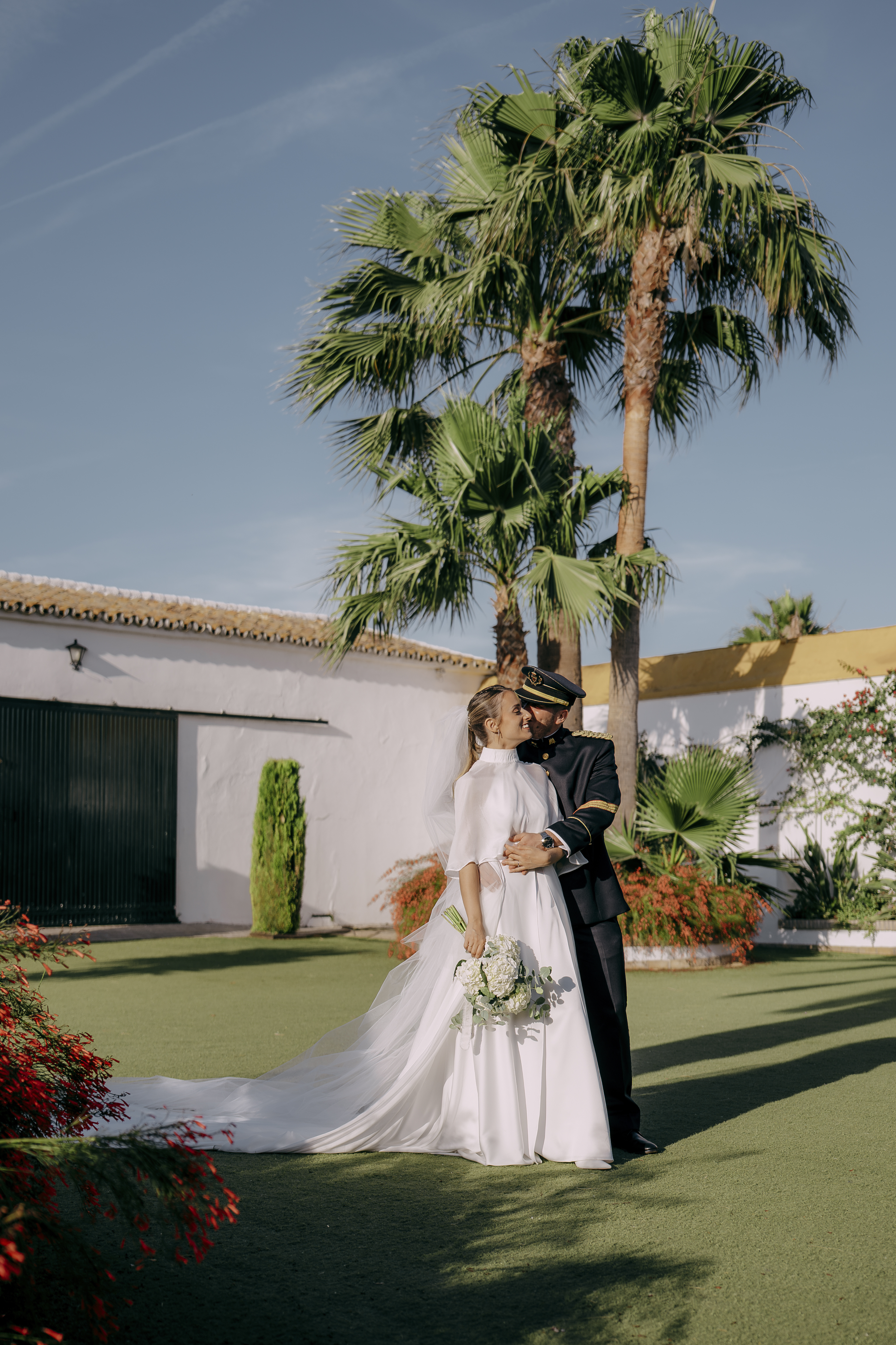 Retrato de cuerpo entero de los novios en un jardín con palmeras