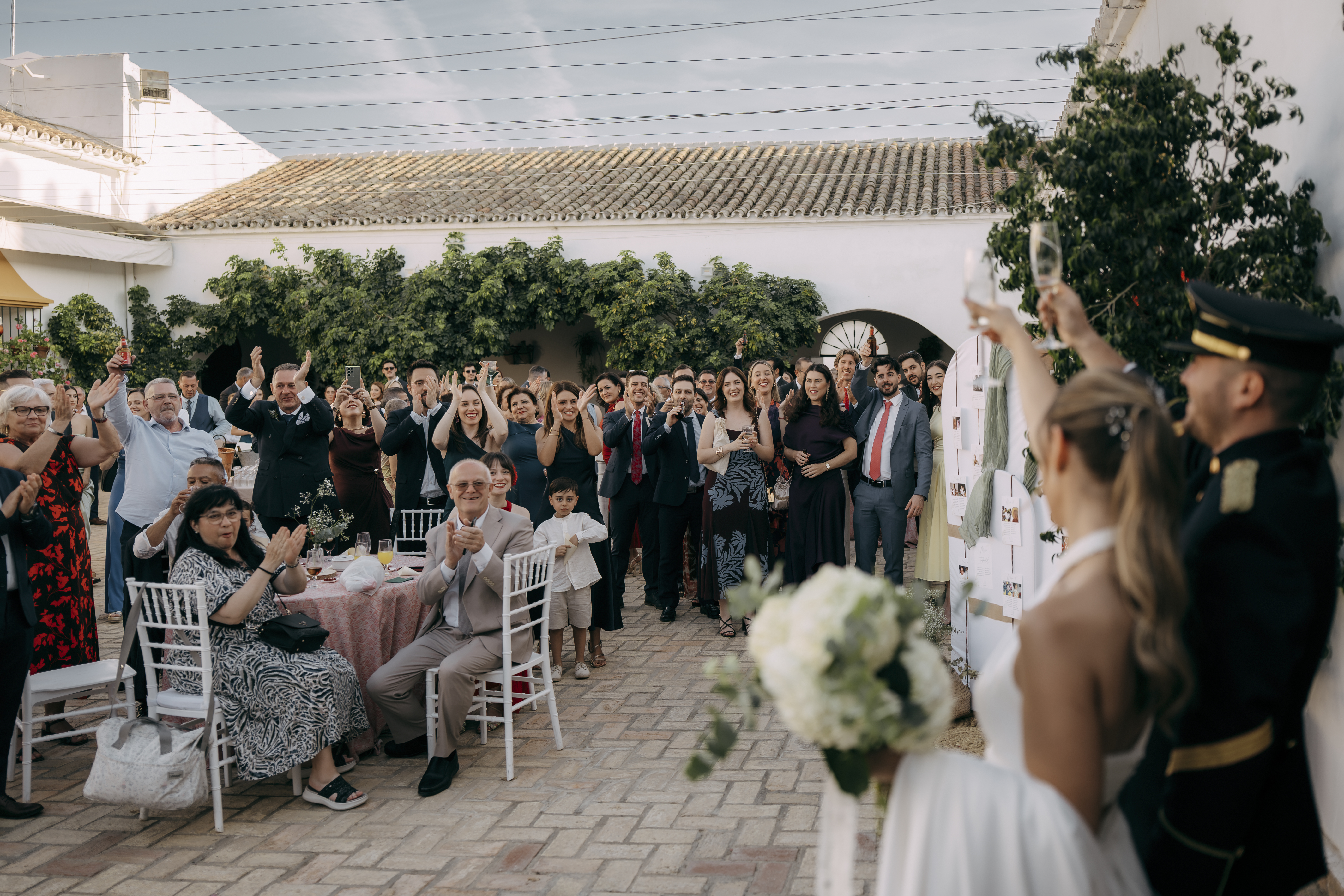Novios brindando entre invitados en el patio de la boda