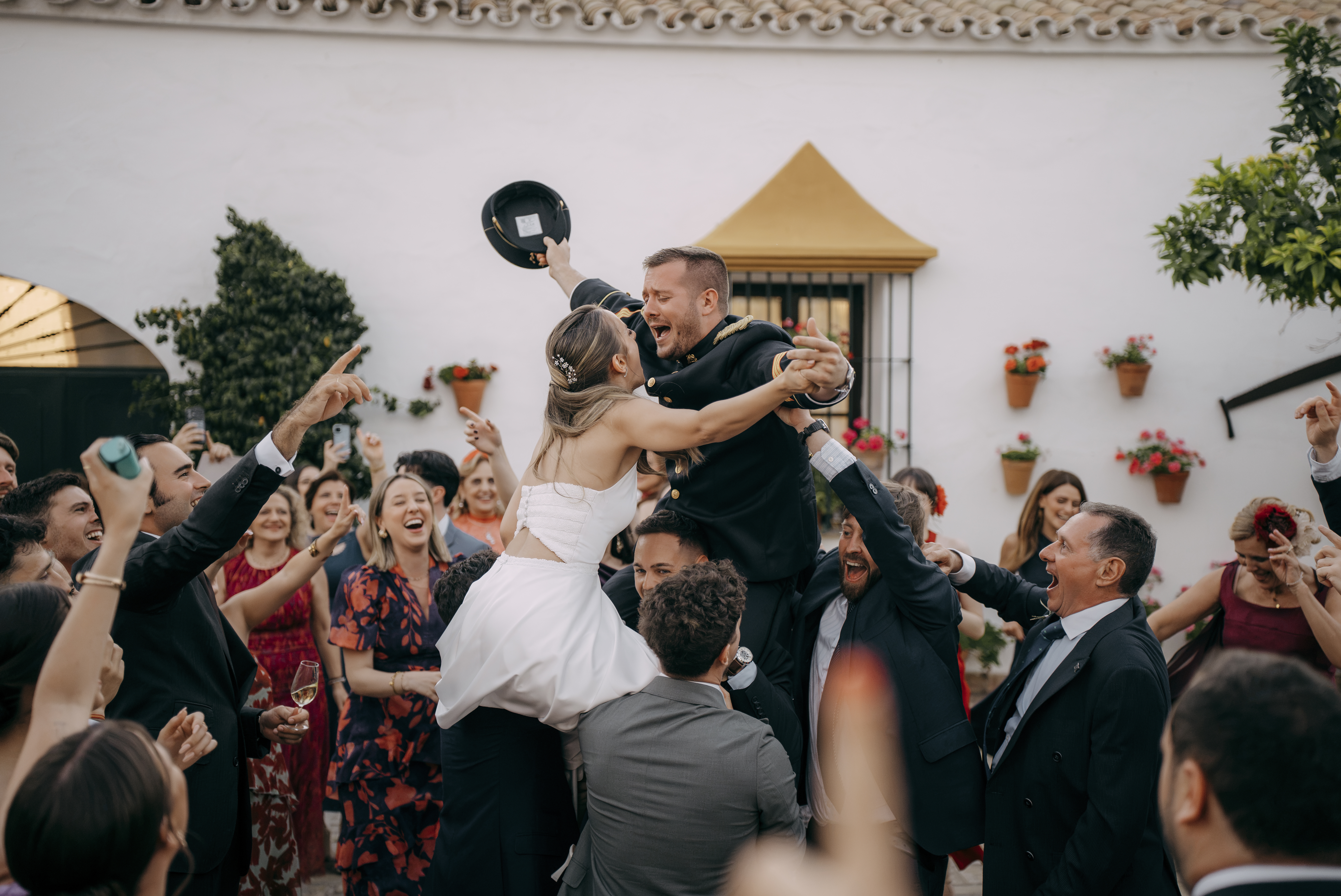 Novios alzados entre los invitados en el patio de la celebración