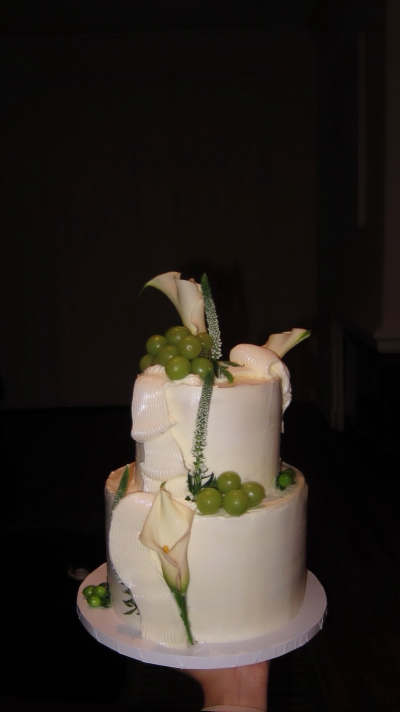 Two-tier white cake decorated with calla lilies and fresh green grapes