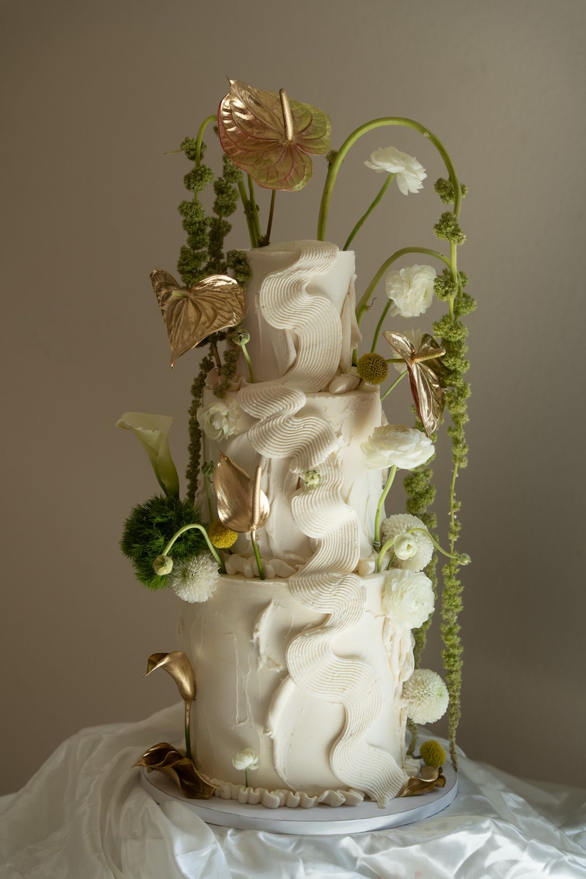 Three-tiered wedding cake with floral and gold accents