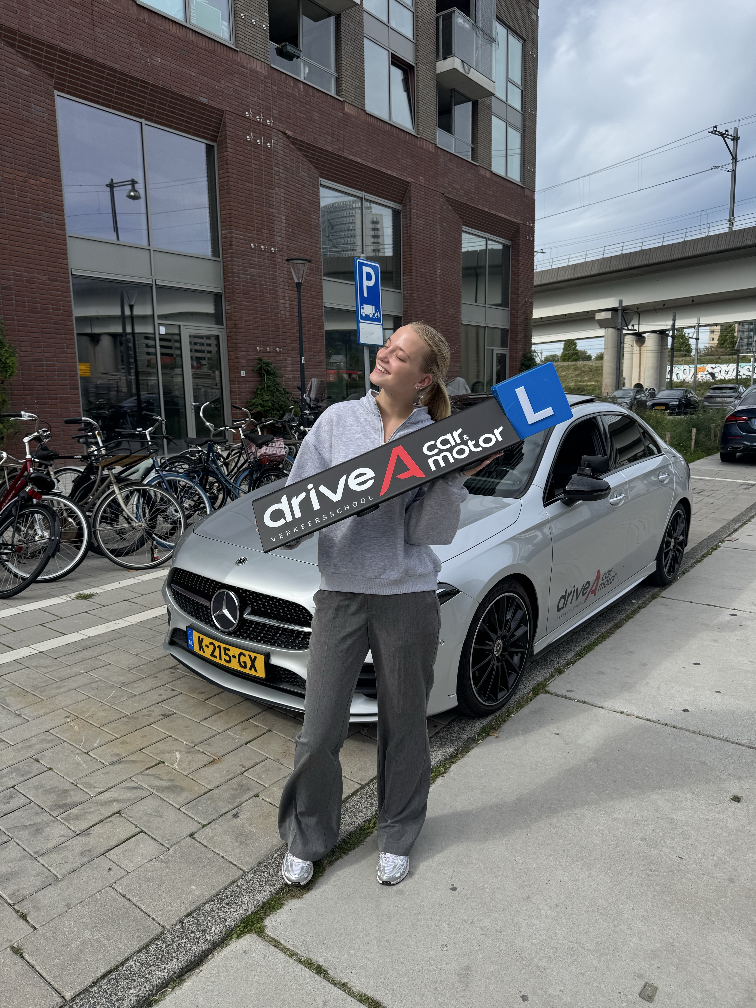 Geslaagde leerling met rijbewijs voor de lesauto van Drive A Car Amsterdam