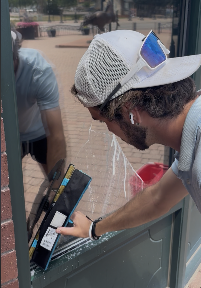 Johnson Exterior Services window cleaner squeegeeing a pane
