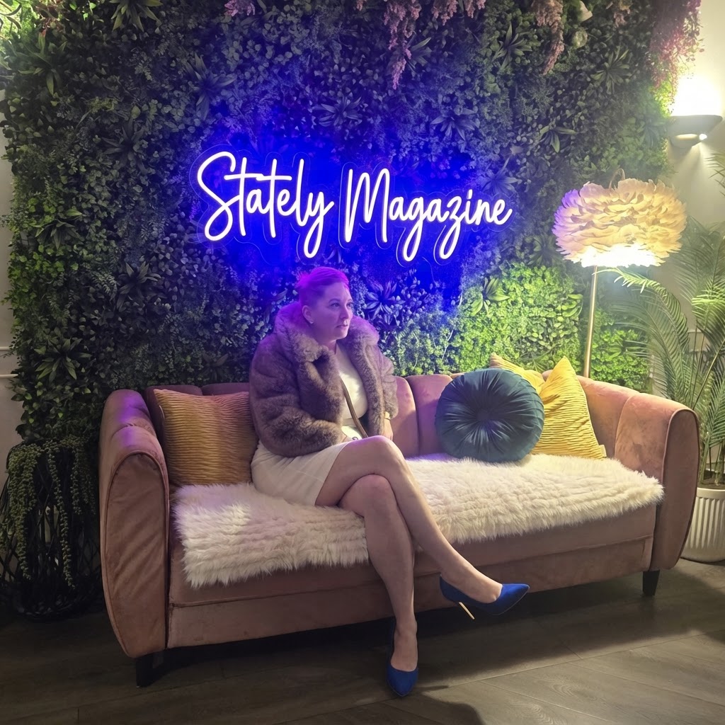 Emma Jane Lindsey seated in a pink velvet lounge beneath a Stately Magazine neon sign