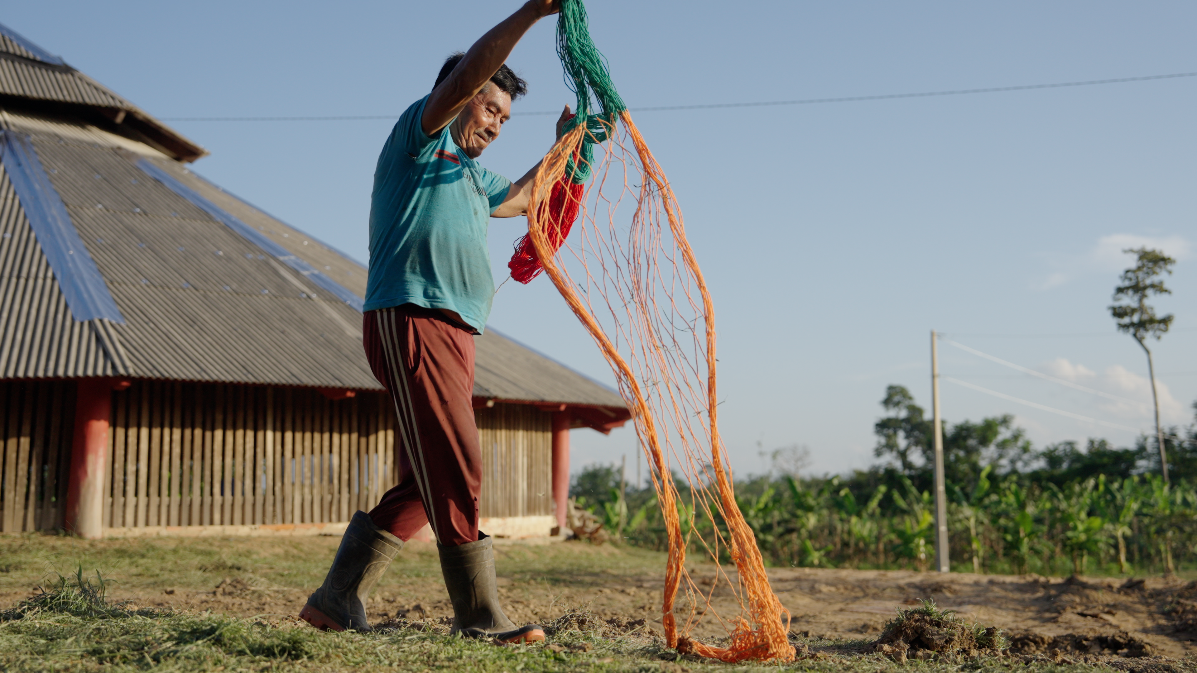 Elderly Indigenous man handling a colorful fishing net