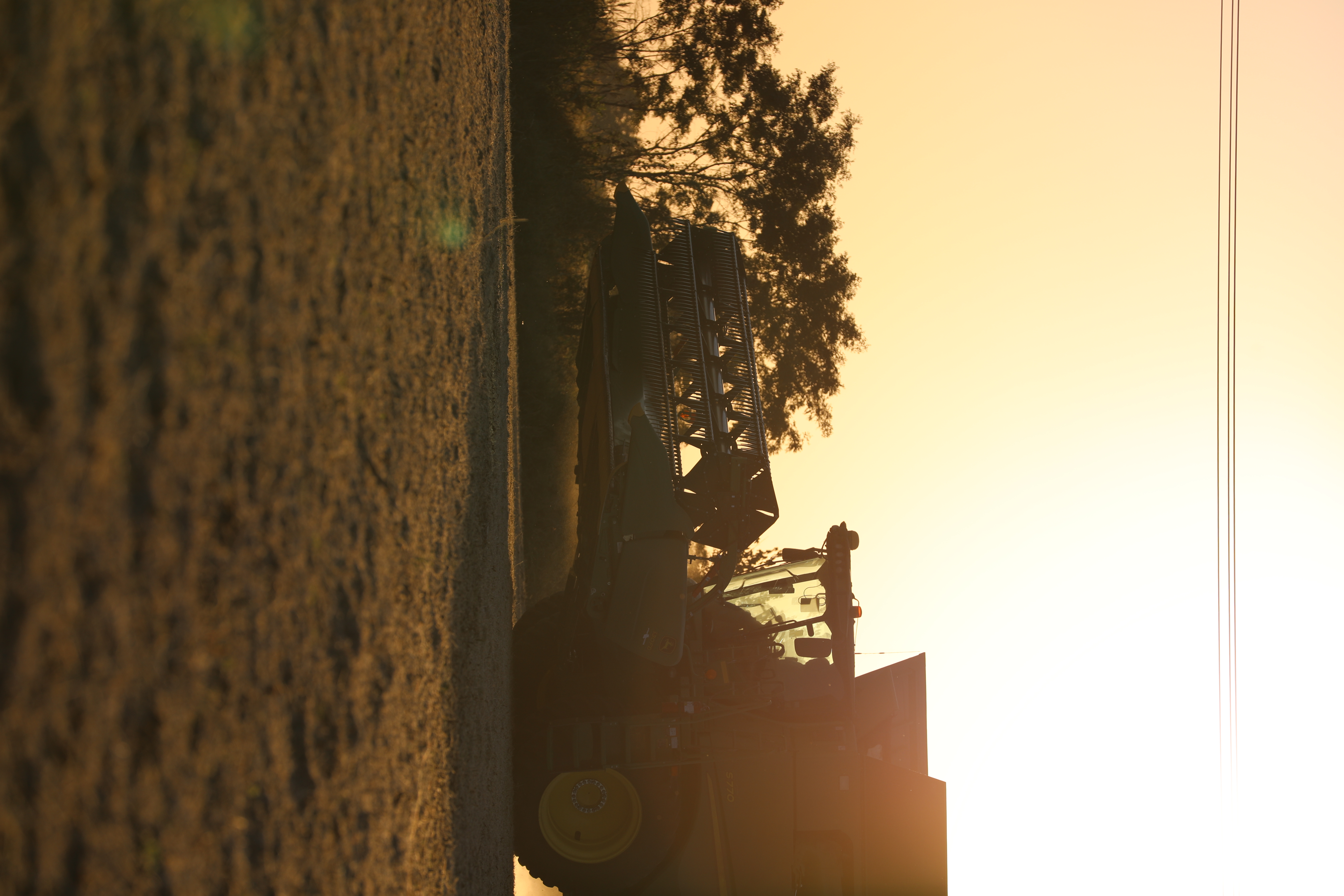 John Deere combine harvester backlit at sunrise