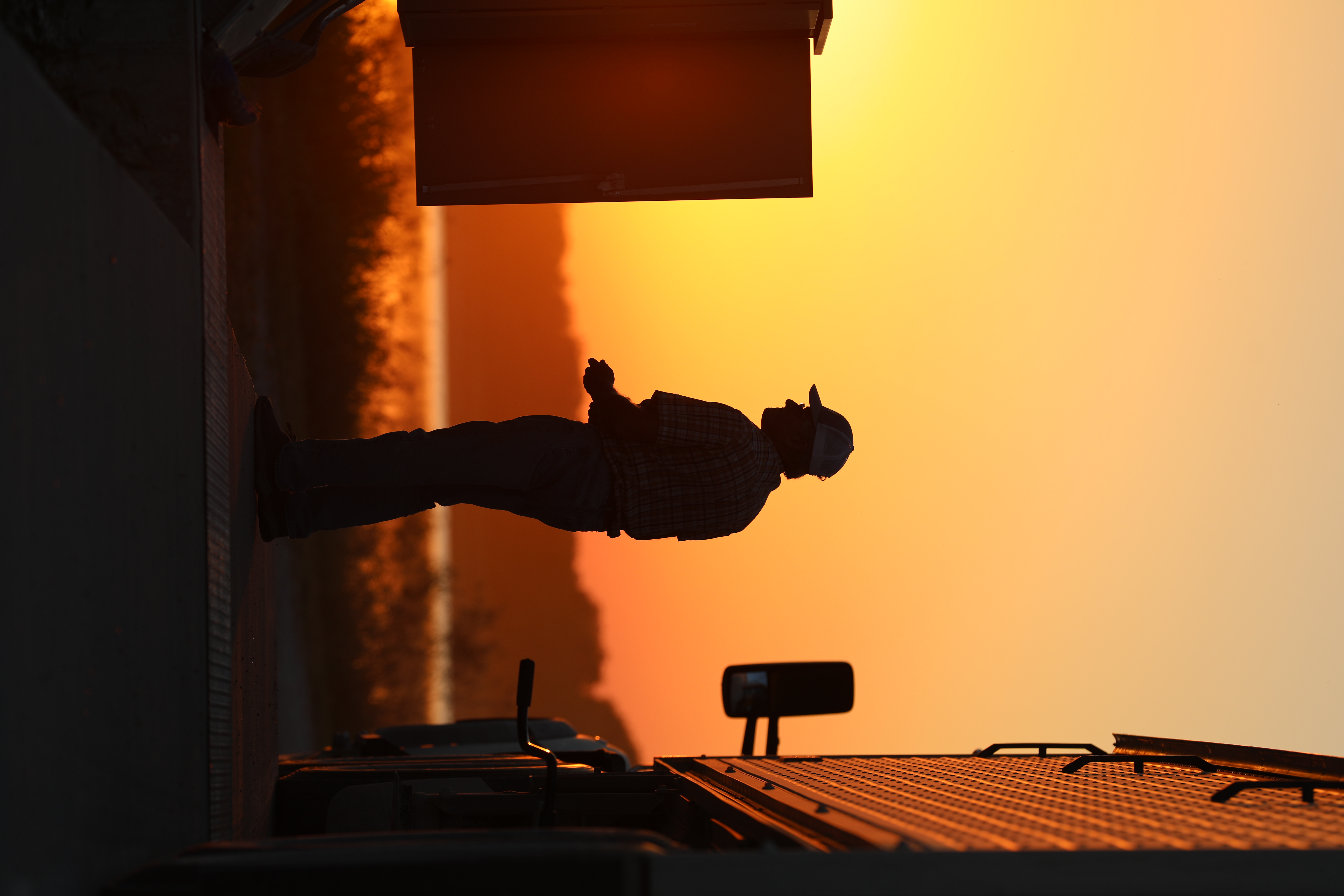 Man in profile beside a utility trailer at golden hour