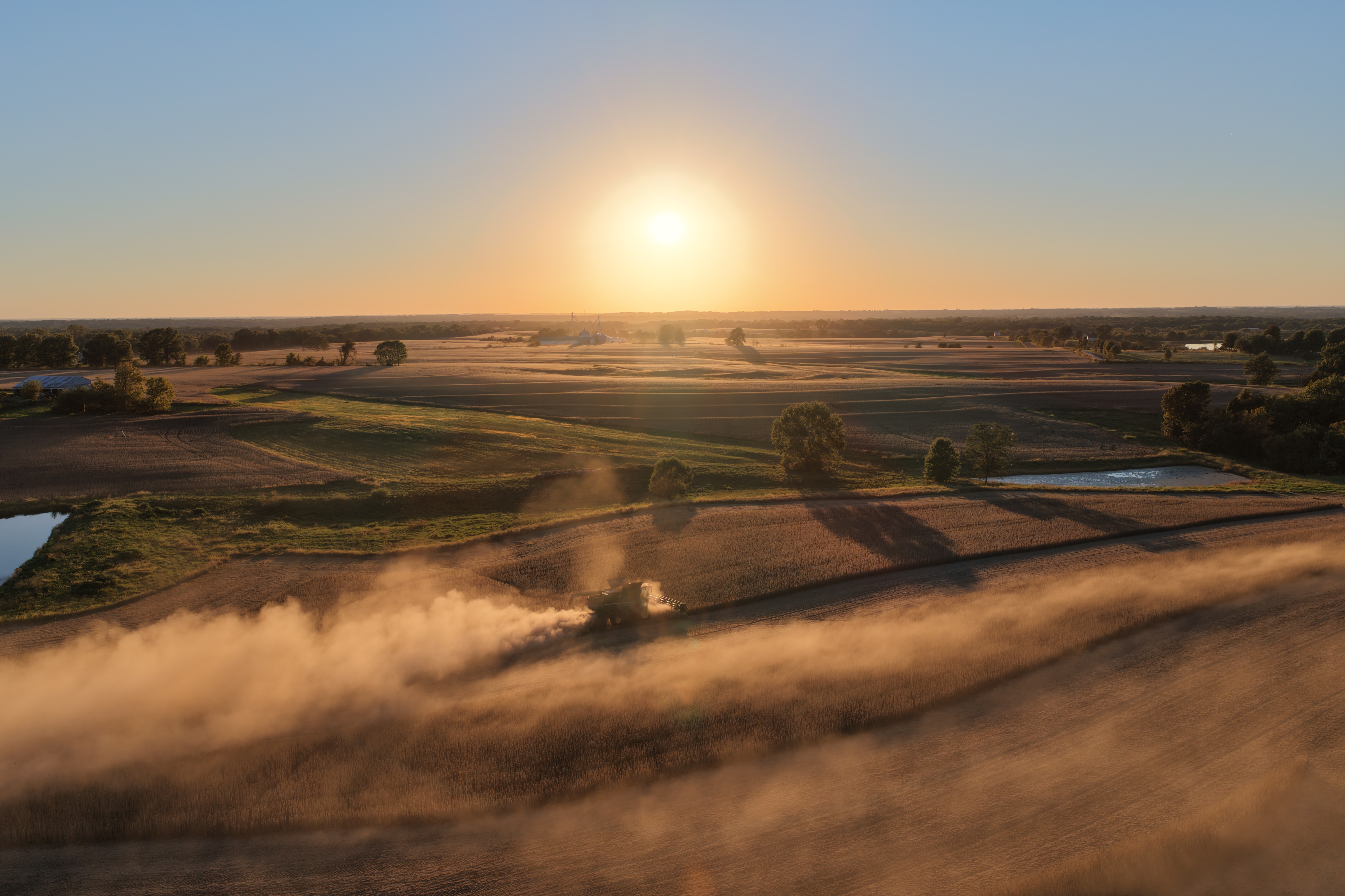 Combine harvester working a golden field at sunset