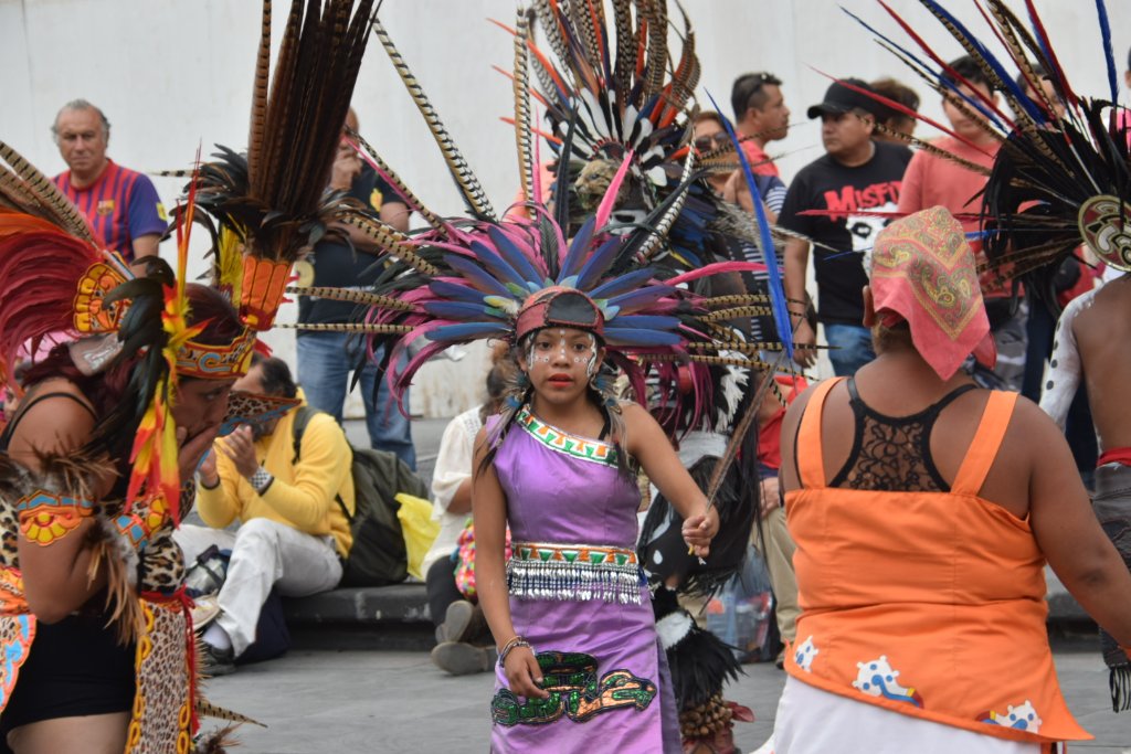 Young female dancer in purple dress and feather headdress