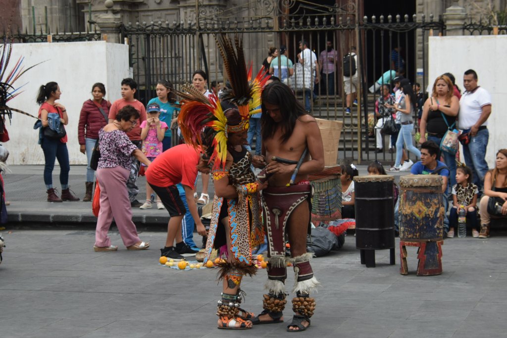 Two dancers in elaborate costumes preparing, drums in background
