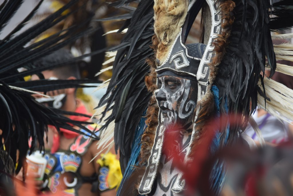 Close-up of dancer with skull mask and dramatic feather crown