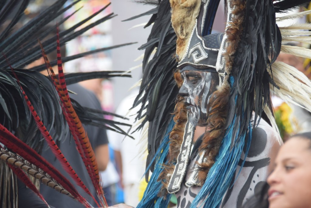 Close-up portrait of dancer with grey face paint and black feather headdress
