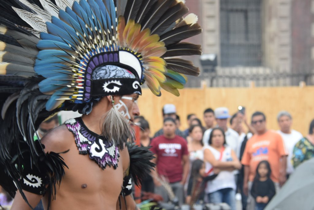 Dancer with feathered headdress facing the crowd outside the Cathedral