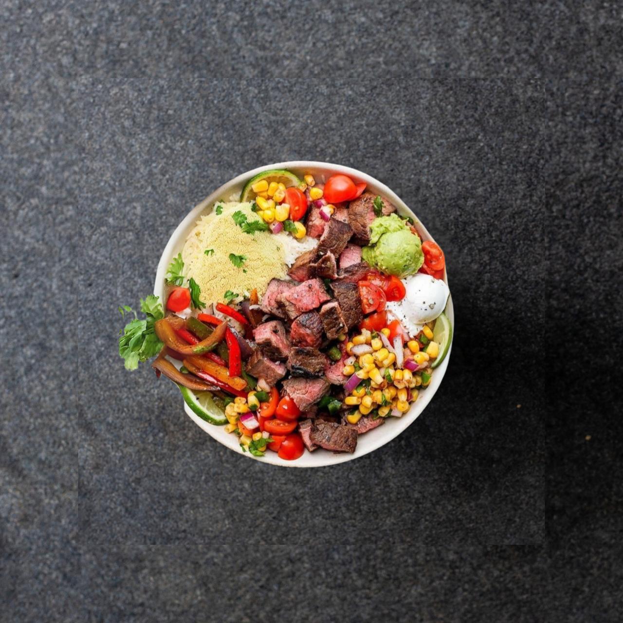 Steak Fajita Bowl Couscous, fajita steak and peppers, corn salsa, guacamole and sour cream