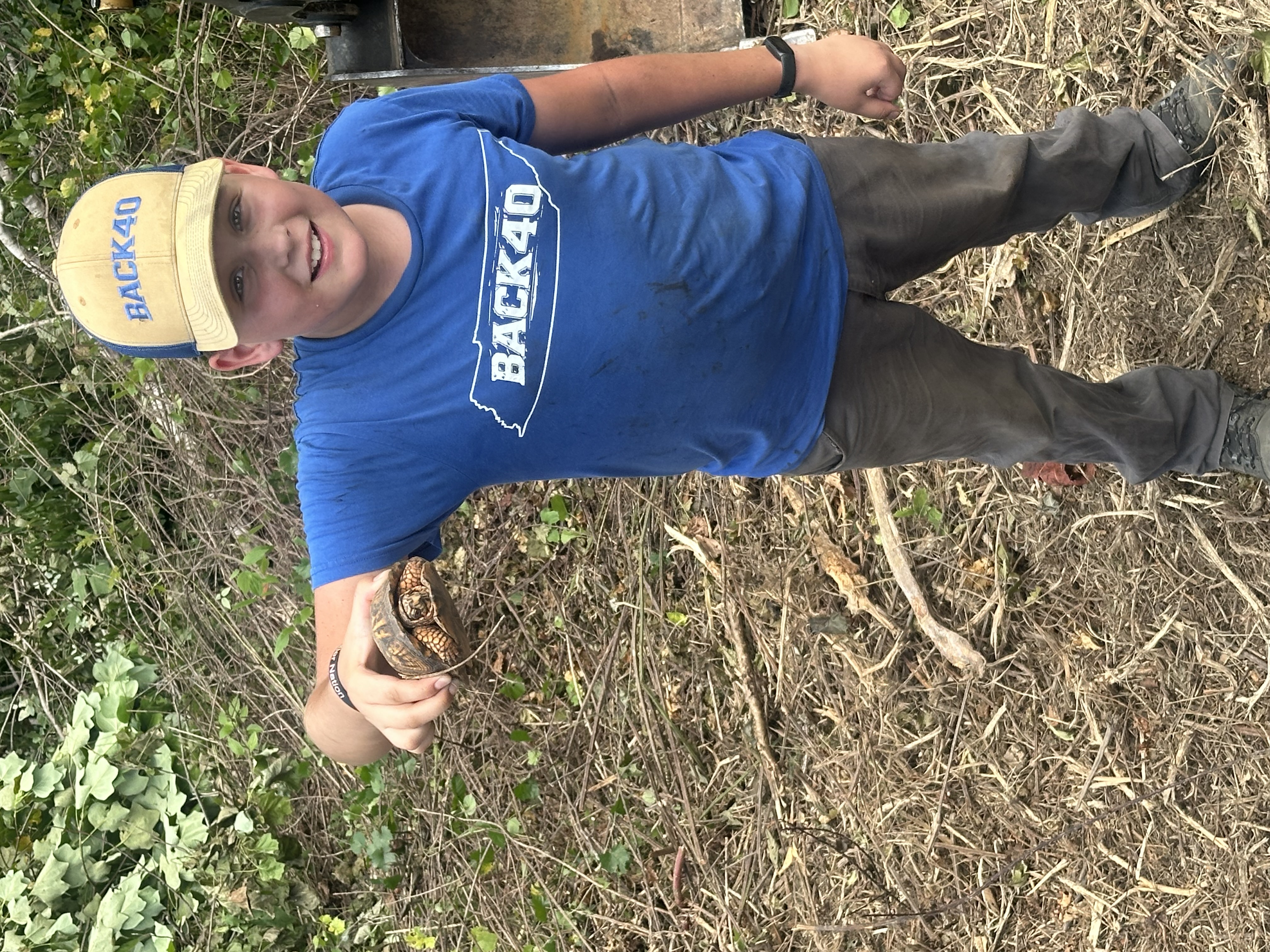 Back 40 Land Services team member in branded gear holding a box turtle safely relocated during land clearing job in Middle Tennessee