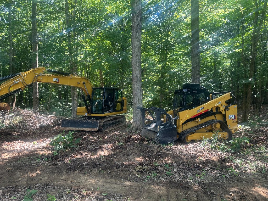 CAT 313 excavator and CAT 275 forestry skid steer working in tandem to clear dense hardwood timber on a residential property in Middle Tennessee