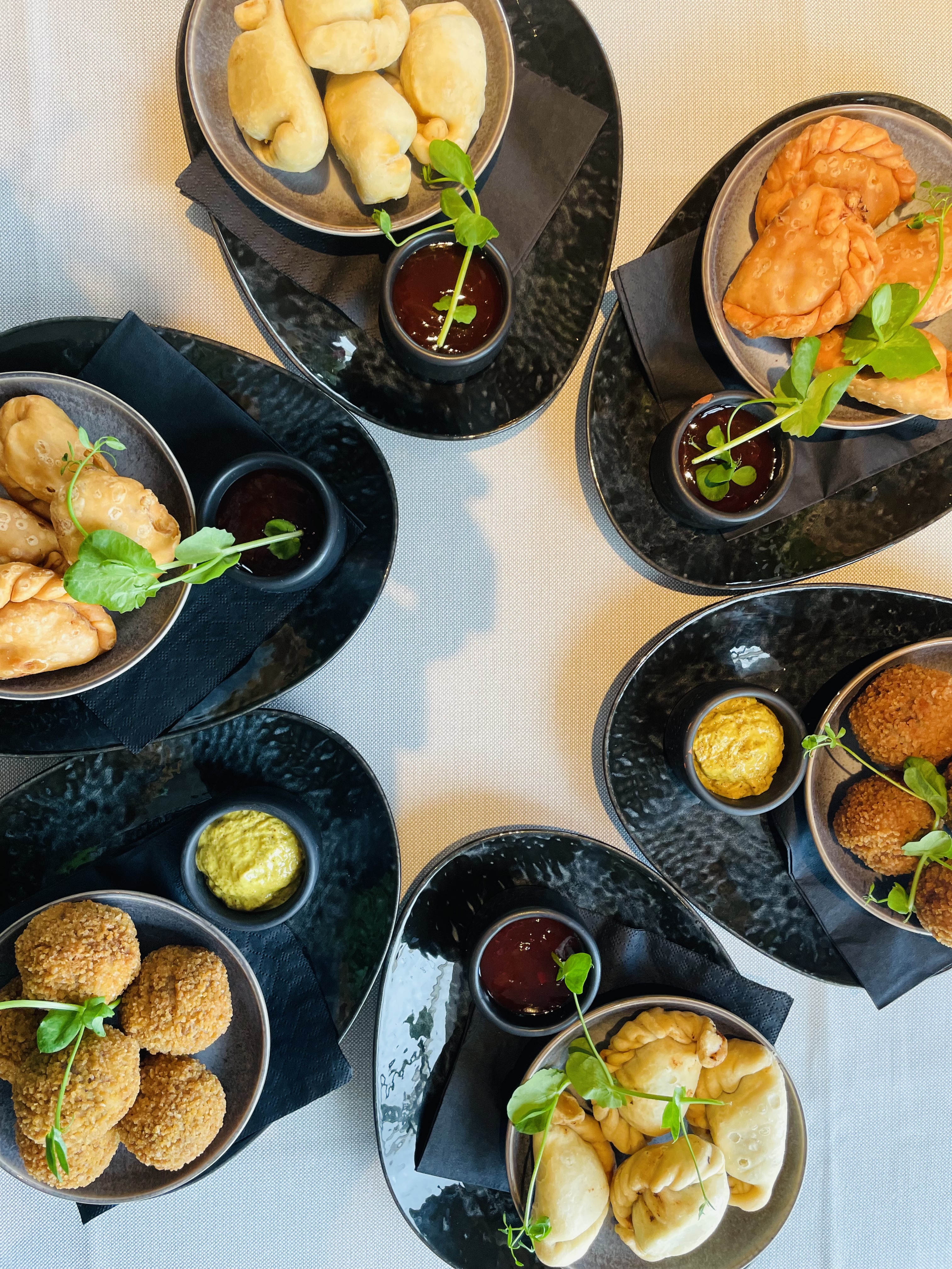 Borrel-Bites van Restaurant LUQS — huisgemaakte empanada's, kroketjes en bitterballen met sausjes op zwarte borden