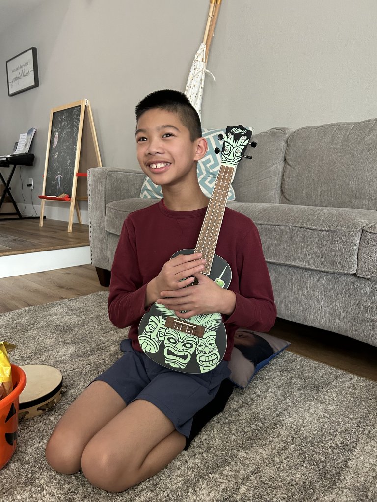Teen smiling and holding a ukulele during a music therapy session