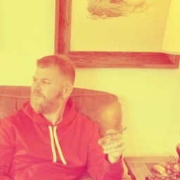 Shane Breen, U.S. Army veteran and Silly Nice Co-Founder, seated indoors wearing a red hooded sweatshirt — documentary portrait