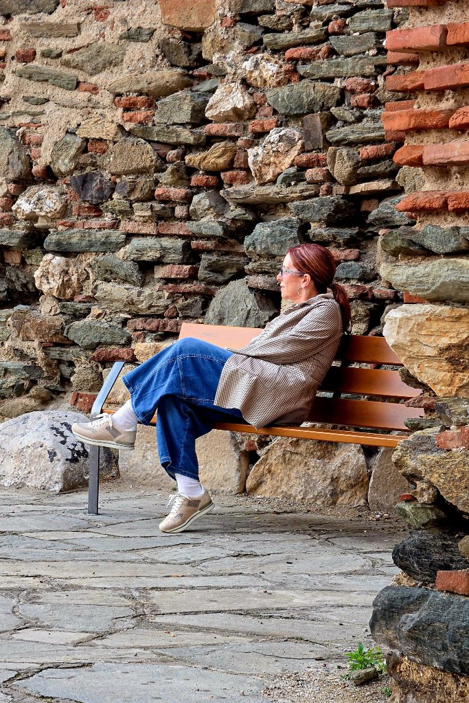 Lady resting on bench by ancient wall — Thessaloniki