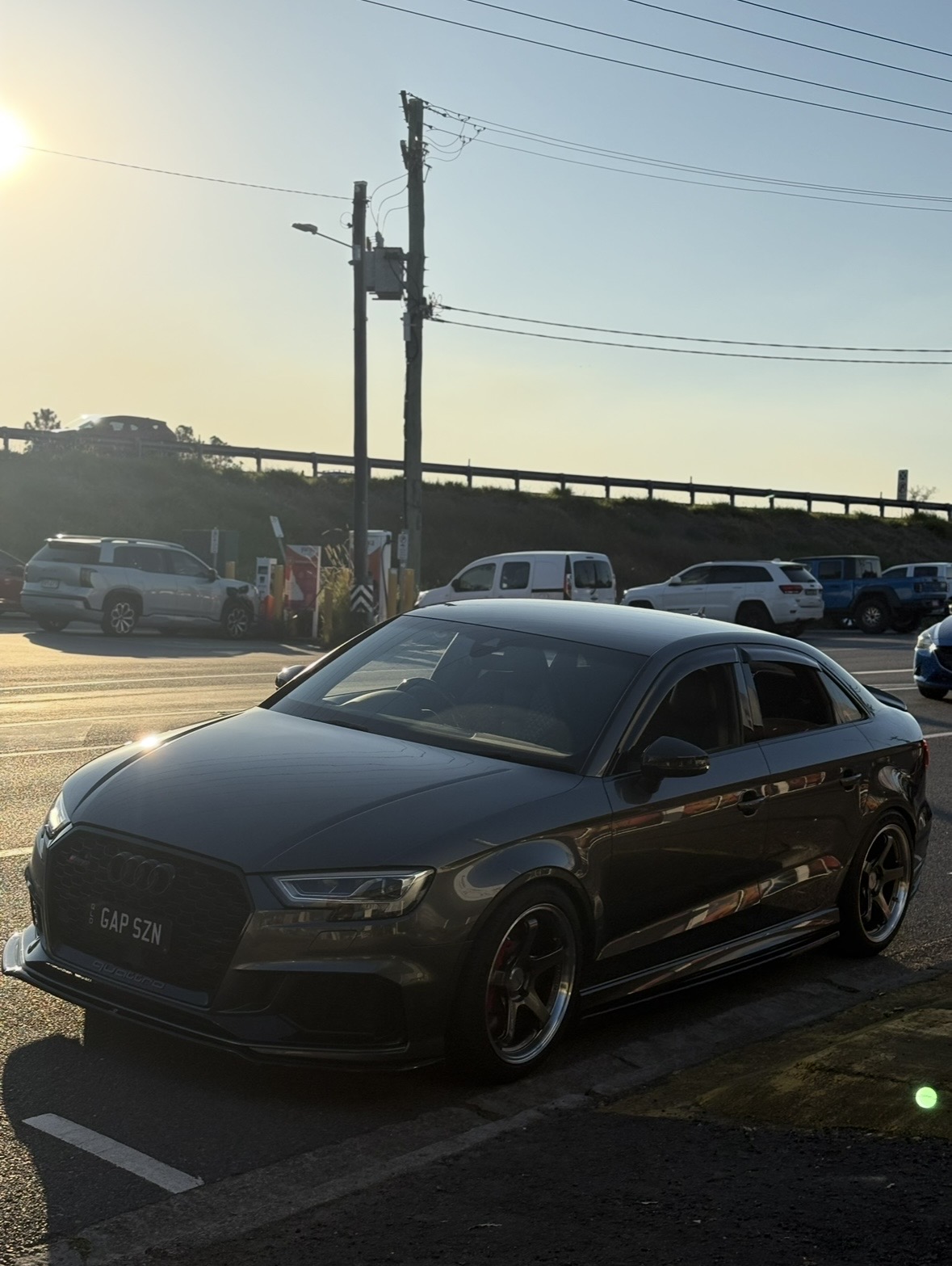 Dark grey Audi RS3 parked on roadside at golden hour