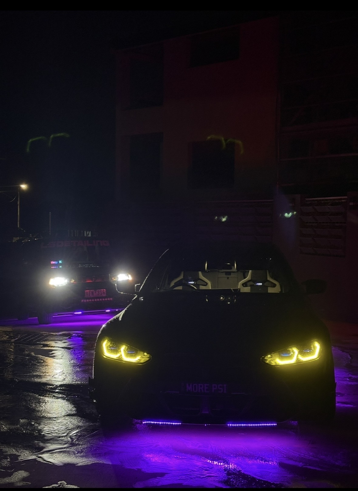Dark BMW sedan at night with purple underglow and yellow angel eye lights