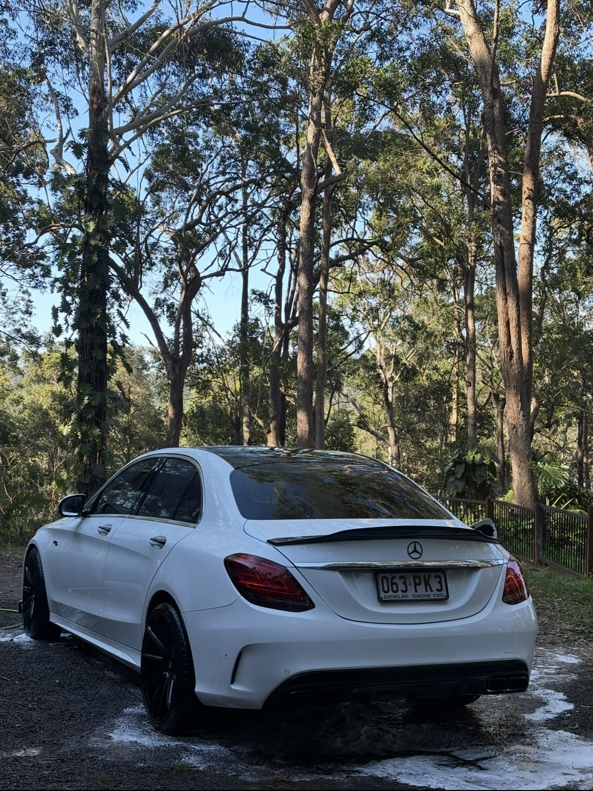 White Mercedes-Benz sedan rear quarter view in bushland setting