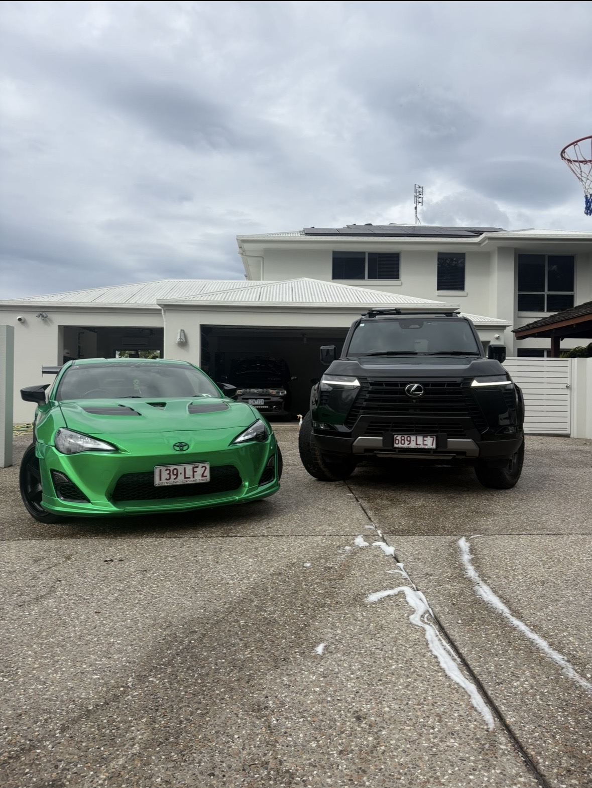 Lime green Toyota 86 and black Lexus LX on driveway after wash