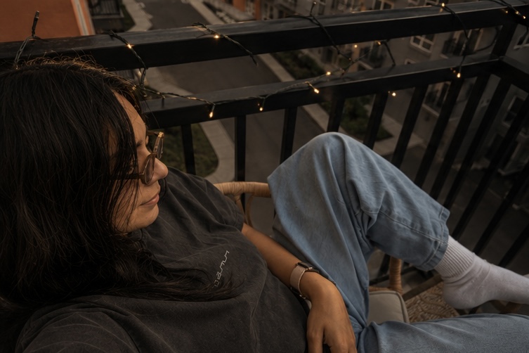Launa Castro on a balcony at dusk, string lights overhead.