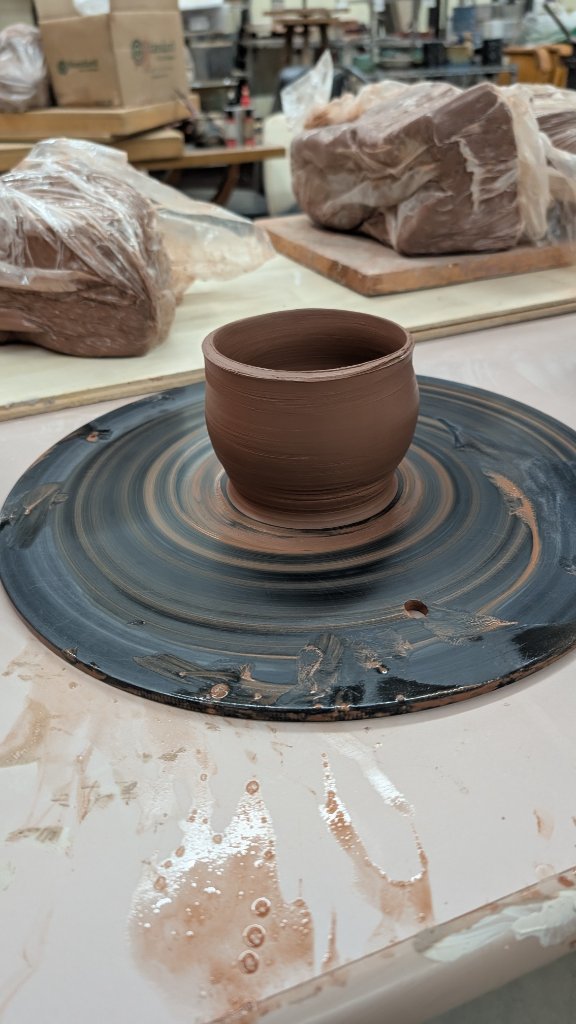 Small clay bowl freshly thrown on wheel in studio