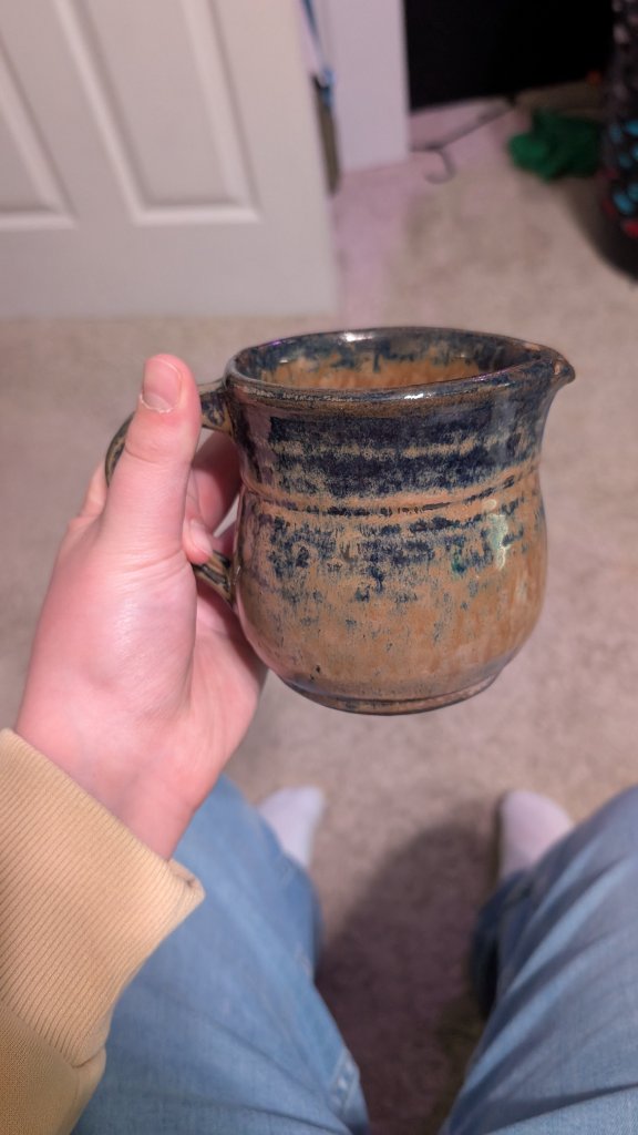 Glazed ceramic pitcher held in hand