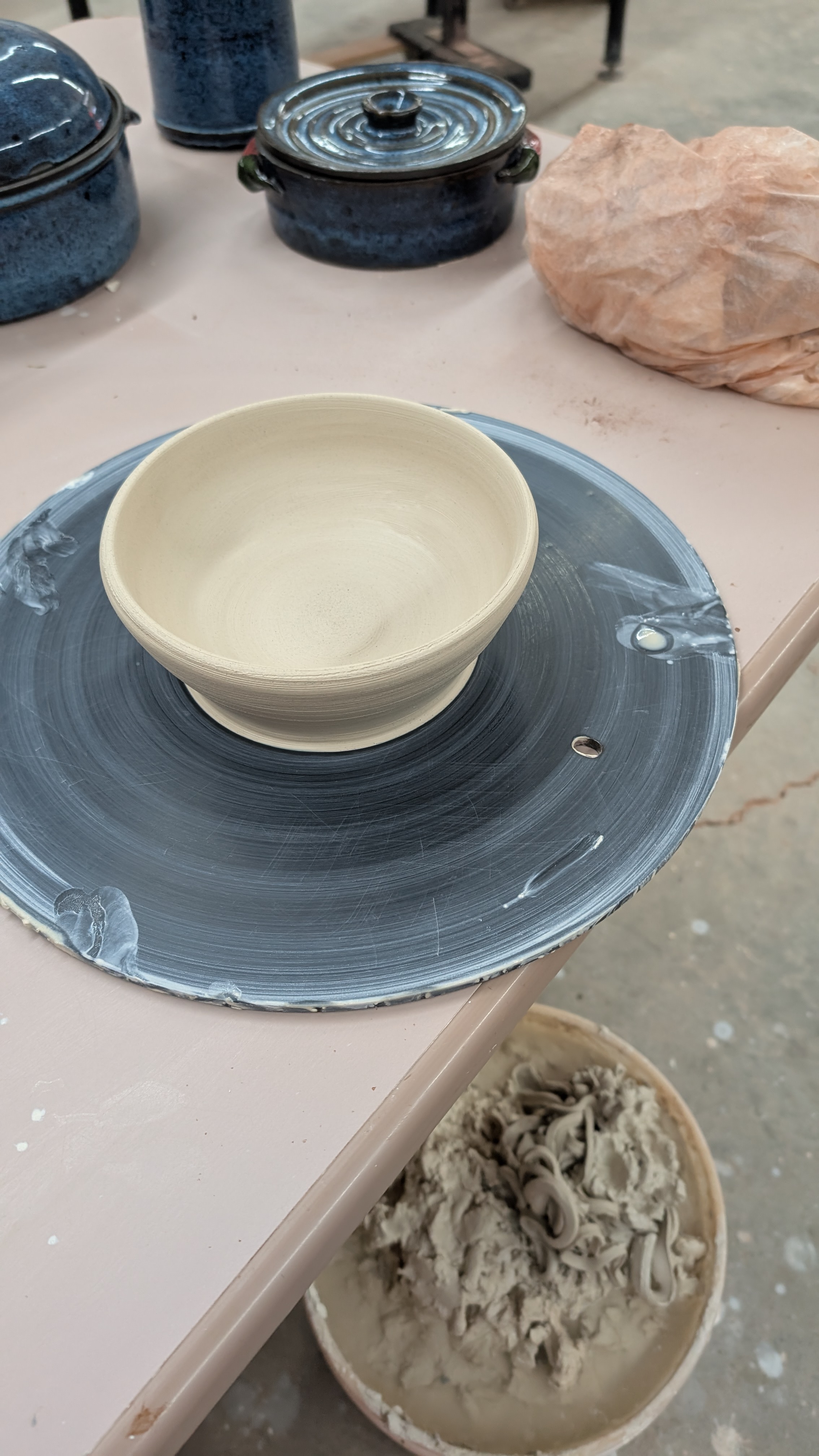 Unfired clay bowl on wheel bat in studio