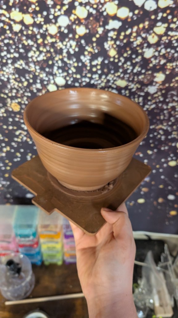 Flared clay bowl held up by hand