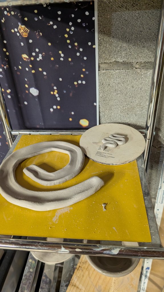 Coiled clay snake and circular tile sculpture
