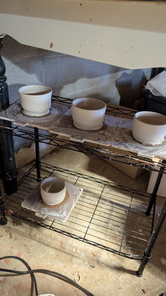 Three clay bowls drying on wire studio rack